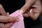 Woman`s hands pin stab the fabric. Tucked up a pink cloth. Preparation for sewing curtains on a black table in the studio.