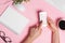 Woman`s hands on a pink office workspace view from above