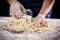 Woman`s hands pour the milk to dough for kneading