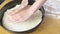 Woman`s hands put the yeast dough on round baking sheet. Making pizza.