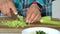 Woman`s hands slicing celery on a wooden cutting.