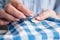 Woman`s hands stitching button on a shirt in tailor shop