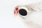 Woman`s hands in sweater holding cup of coffee on white table. Top view, styled stock image. Break, breakfast concept.