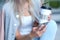 Woman`s hands using phone and holding paper cup with coffee. Teen hipster online internet consept