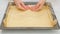 Woman`s hands using plastic wrap unfurl pizza dough onto prepared baking pan. Homemade pizza