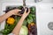 Woman`s hands washing eggplant and other vegetables for preparing salad top view