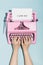 Woman`s hands writing `I love you` on an oldschool pink typewriter.