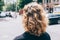 Woman`s head with curly brown hair, back view