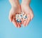 Woman`s holding cupped hand full of pills, view from above