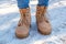 Woman`s legs at the brown boots standing on snow