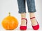 Woman`s legs, fashionable shoes and ripe pumpkin