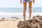 The woman`s legs stand on the rocks in the beach