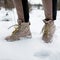 Woman`s legs in stylish pants in winter brown leather fashion boots on snow. Close-up