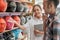 A woman`s shop assistant holding a tablet in a hand gesture offers a helmet to the man