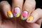 Woman\\\'s short fingernails with colorful spring themed nail polish with tulip flower art deisgn