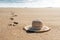 Woman`s straw beach hat on the sand on the beach, and footprints leading to the sea. Beautiful sunny day.  Vacation, Summer