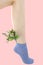 Woman`s unshaven leg in blue socks on a pink background. Pink flowers is in the socks