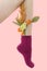 Woman`s unshaven leg in dark pink socks on a pink background. Yellow flowers is in the socks