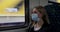 Woman with safety face mask sitting in train and looking through the window. virus pandemic