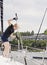 Woman on sailboat with boat hook grabbing rope for mooring ball