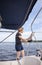 Woman sailing holding ropes to adjust sails on sailboat