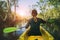 Woman sailing kayak in mangrove forest against beautiful sun light