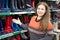 Woman salesman standing near store shelves and showing waterboots