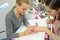 Woman in salon receiving manicure by nail beautician