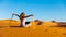 Woman through sand in the sahara desert with computer