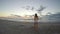 Woman on sandy beach running towards the sea