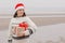 woman in a Santa Claus hat with a gift box in her hands smiles. a happy European woman carries a gift for New Year or