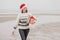 woman in a Santa Claus hat with a gift box in her hands smiles. a happy European woman carries a gift for New Year or