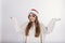 Woman in santa claus hat spread wide her hands and looking at camera with anxious face