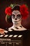 Woman in santa muerte mask behind clapboard