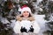 A woman in Santa's hat holds a snowball in her hands in a snow-covered winter forest, a place for text