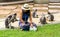 Woman in sarong and whit fedora sitting on ground surrounded by dusky monkeys