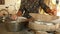 Woman sat cross-legged using hand-turned millstone to grind wet rice for making soaked rice flour 