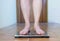 Woman on scales. Female stepping on weighing scales. Feet measuring body weight or overweight, close up