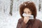 Woman with scarf blowing nose in wood in winter