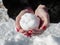 A woman with a scarlet manicured nails makes a snowballon a path covered with snow.