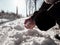 A woman with a scarlet manicured nails makes a snowballon a path covered with snow.