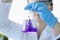 Woman scientist dripping purple liquid into flask with solvent closeup