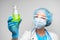 Woman scientist holding laboratory flask with chemical liquid, gray background