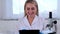 Woman scientist research chemist in a medical suit and protective gloves with a tablet computer and a microscope