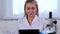 Woman scientist research chemist in a medical suit and protective gloves with a tablet computer and a microscope