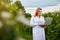 Woman scientist working in fruit garden. Biologist inspector examines blackberry bushes using laptop