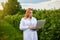 Woman scientist working in fruit garden. Biologist inspector examines blackberry bushes using laptop