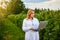 Woman scientist working in fruit garden. Biologist inspector examines blackberry bushes using laptop