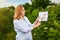 Woman scientist working in fruit garden and shows the level of crop growth using infographics. Biologist inspector examines blackb