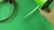 Woman scissors cut green ribbon on green background.